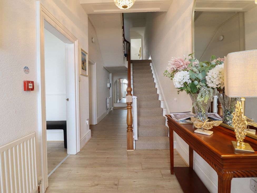 A hallway with a staircase and a console table at Sea View, East Parade in Llandudno
