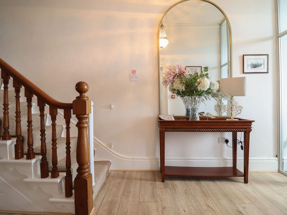 An entrance hall with a staircase and table at Sea View, East Parade Llandudno