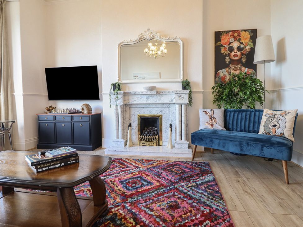 A living room with a fireplace and furniture at Sea View, East Parade Llandudno