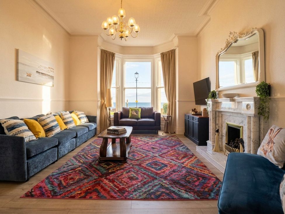 A living room with a sofa, armchair, and coffee table at Sea View, East Parade Llandudno