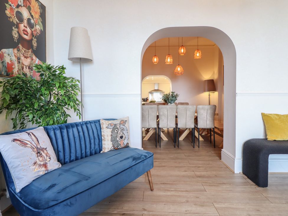 A living room with a blue sofa and dining area at Sea View, East Parade in Llandudno
