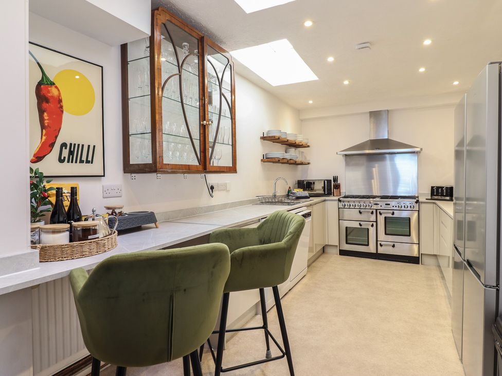 A kitchen with bar stools and appliances at Sea View, East Parade in Llandudno