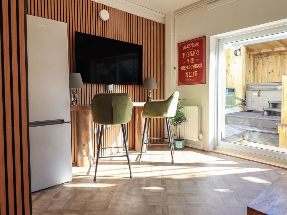 A kitchen with a refrigerator, television, and bar stools at Sea View, East Parade in Llandudno