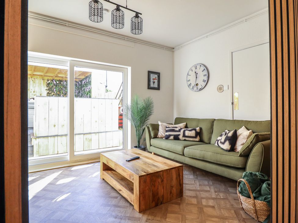 A living room with a green sofa and wooden coffee table at Sea View, East Parade in Llandudno