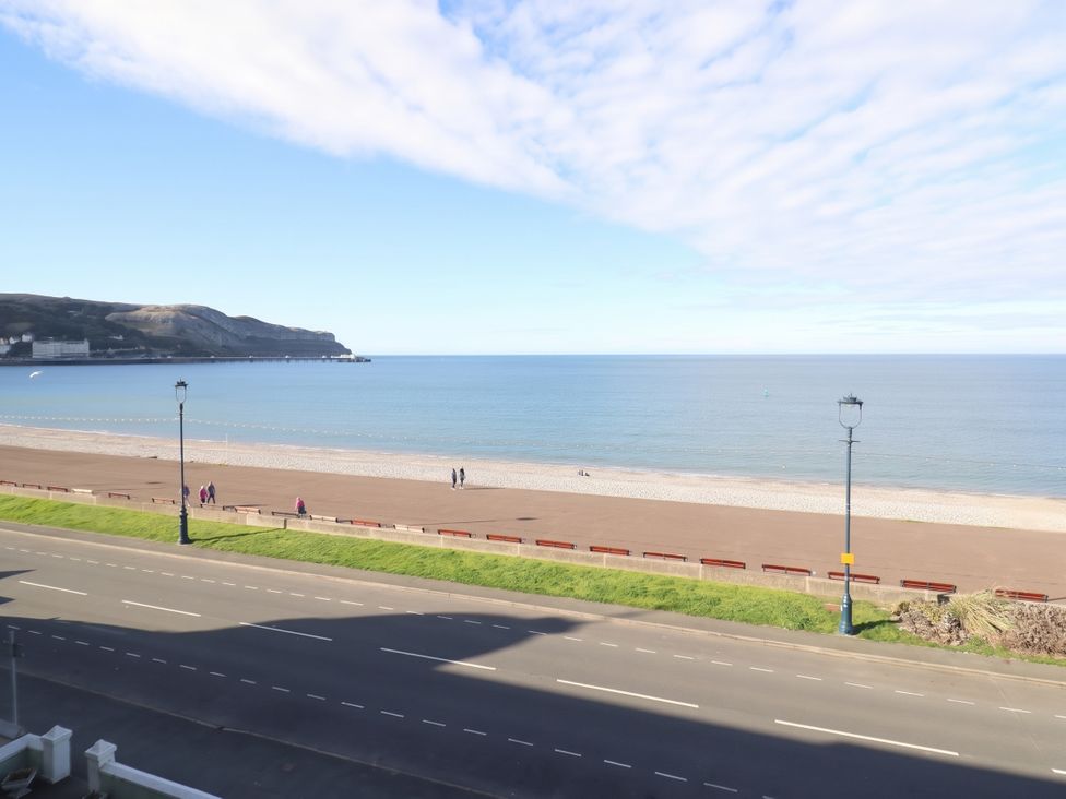 A beach view with people walking along the shore at Sea View, East Parade Llandudno