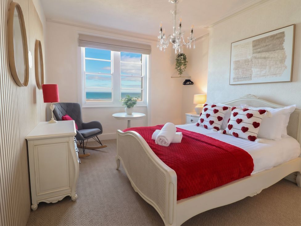 A bedroom with a bed and windows at Sea View, East Parade in Llandudno