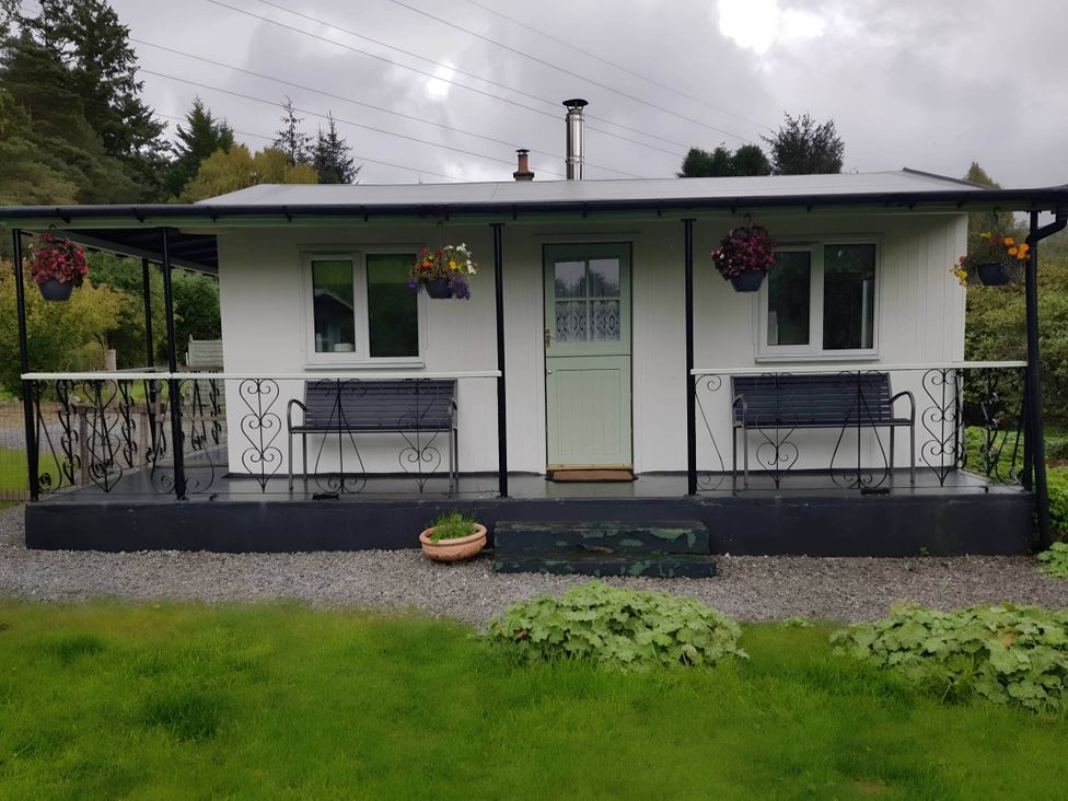 A cottage with a green door and flower pots at River View Cottage Sleeps 6 - Garden, Bbq, Parking in Pitlochry