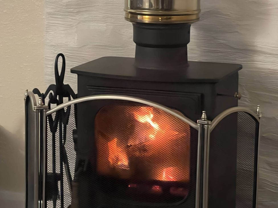 A fireplace with burning wood in a living room at River View Cottage Sleeps 6 - Garden, Bbq, Parking in Pitlochry