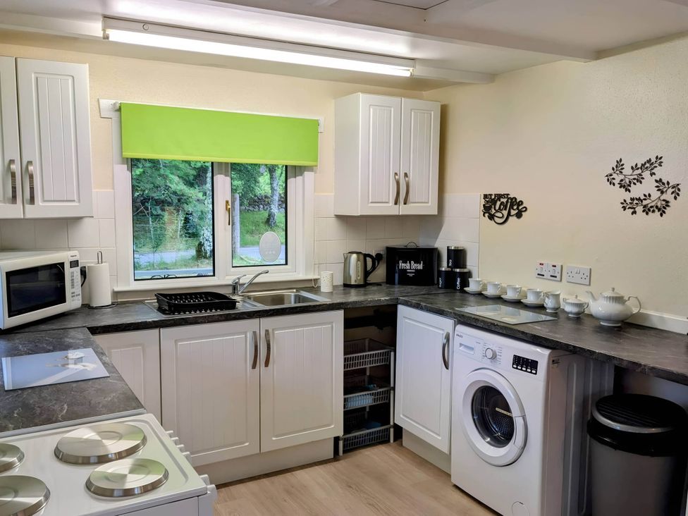 A kitchen with a sink, stove, and washing machine at River View Cottage Sleeps 6 - Garden, Bbq, Parking, Pitlochry