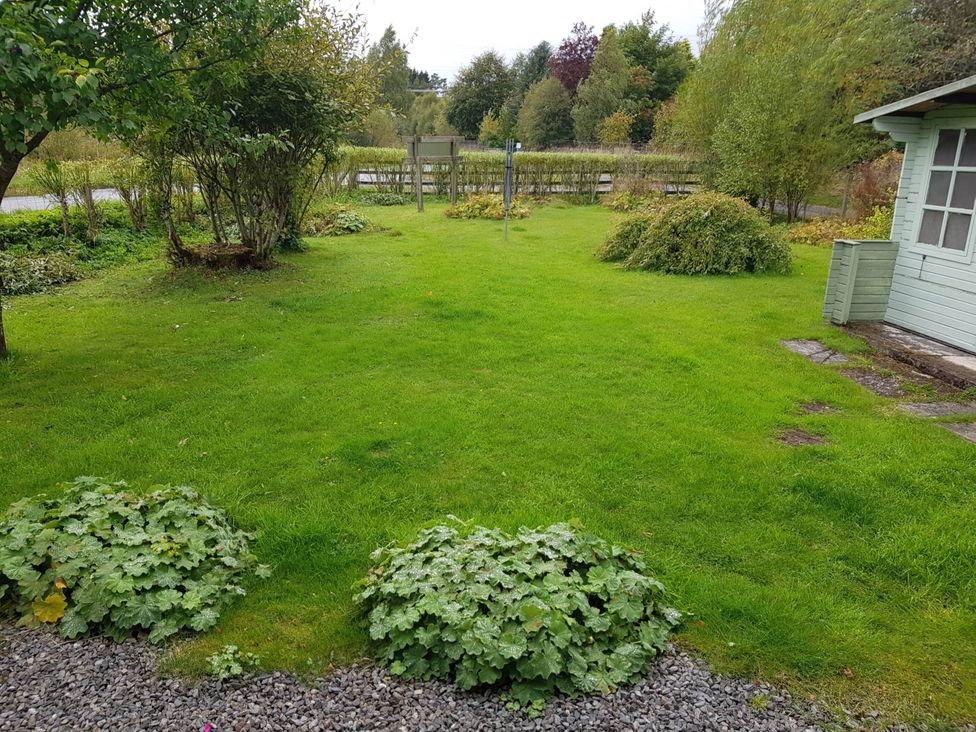 A garden with grass, bushes, and a garden shed at River View Cottage Sleeps 6 - Garden, Bbq, Parking in Pitlochry