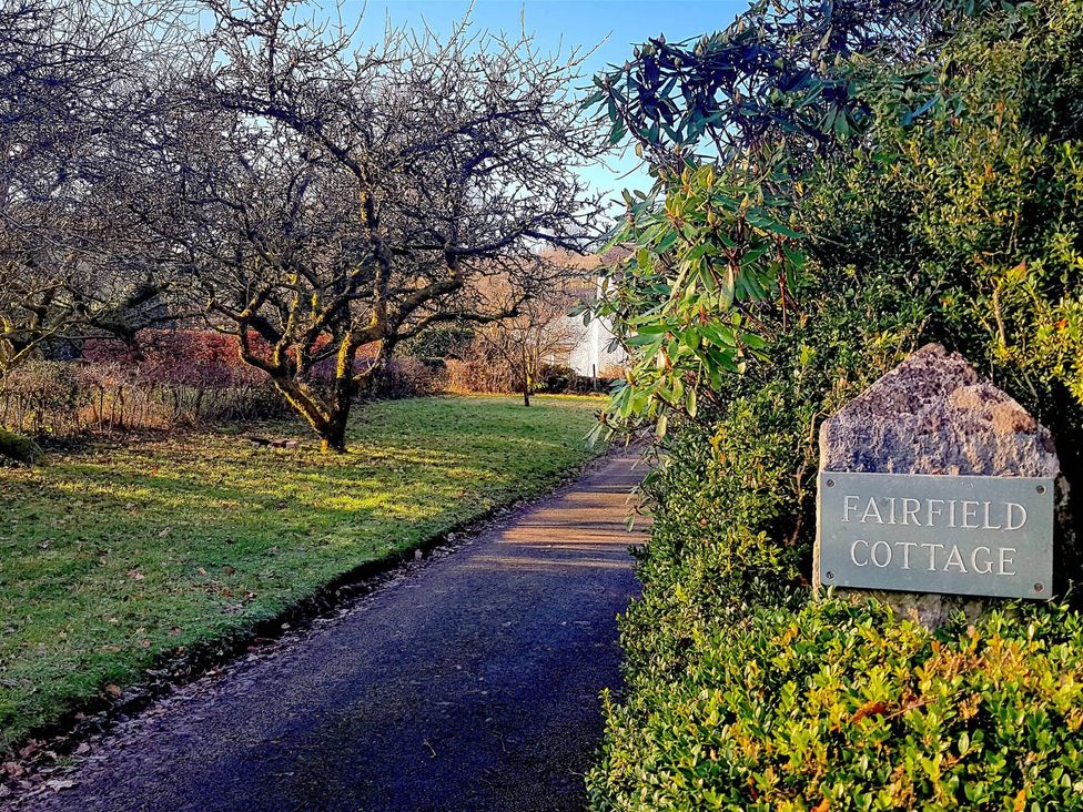A pathway alongside trees and a sign for Fairfield Cottage