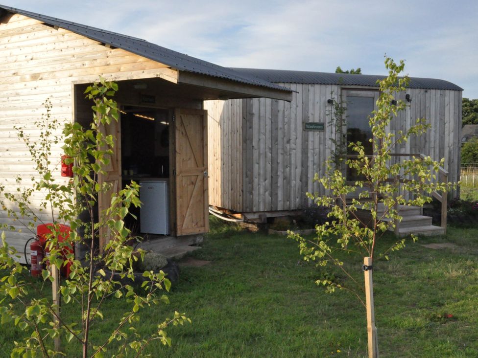 Two wooden structures with doors in a grassy area at Restored circus wagon Saltburn-By-The-Sea