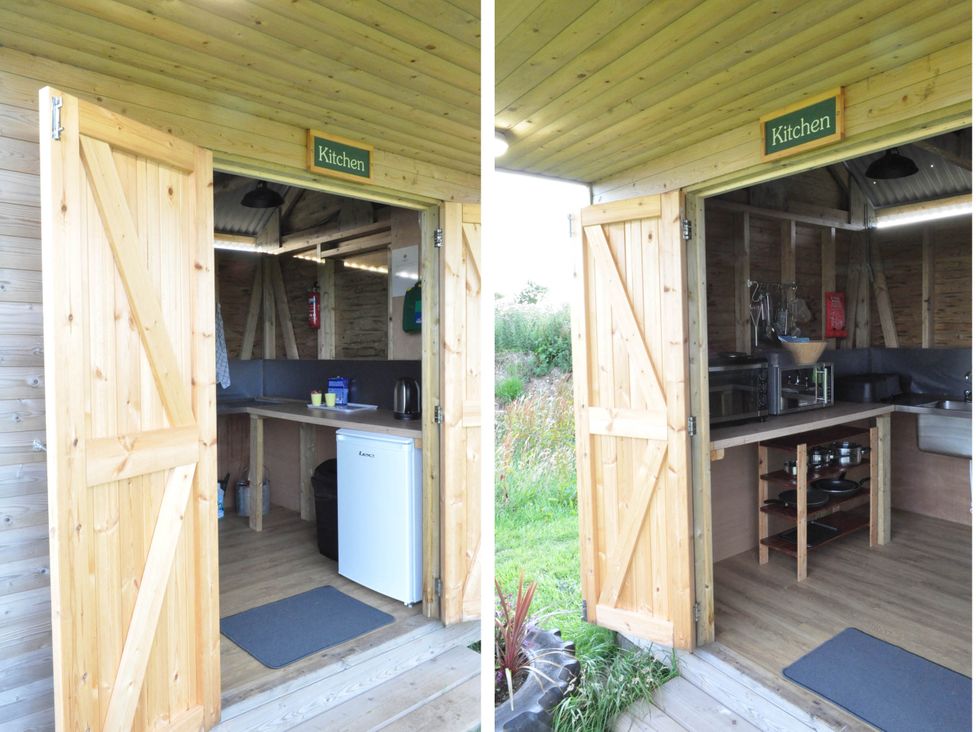 A kitchen with wooden doors open and appliances visible at Restored circus wagon Saltburn-By-The-Sea