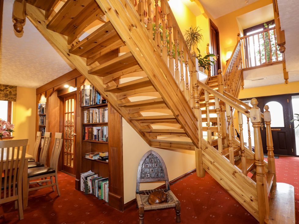 A hallway with a wooden staircase and dining area at Dunhallin House in Inverness