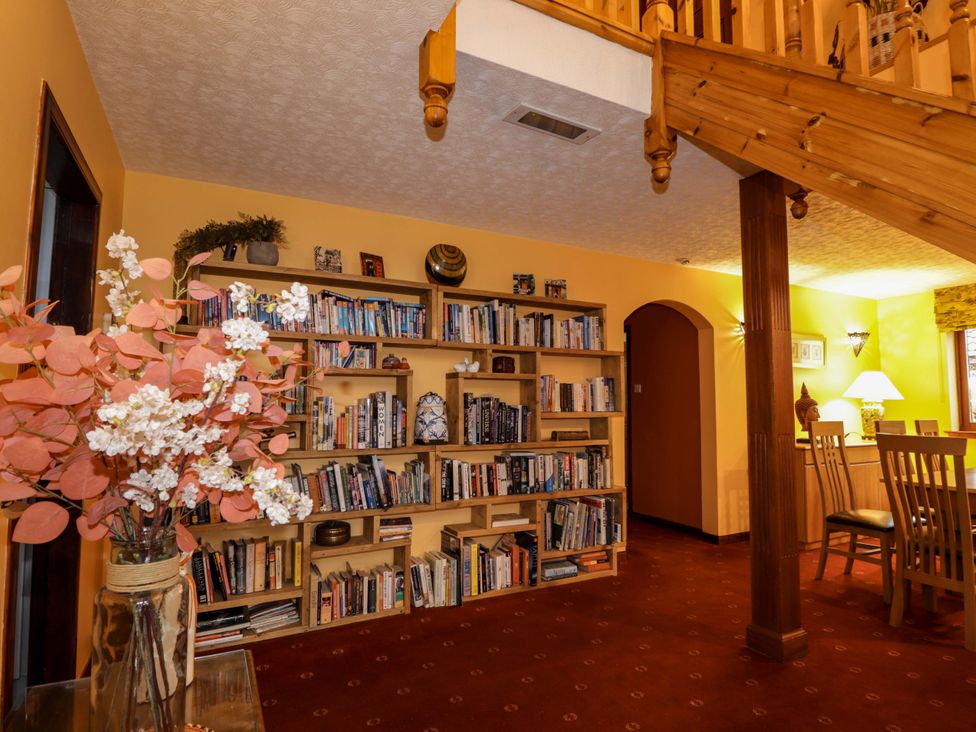 A living room with a bookshelf and a dining area at Dunhallin House in Inverness