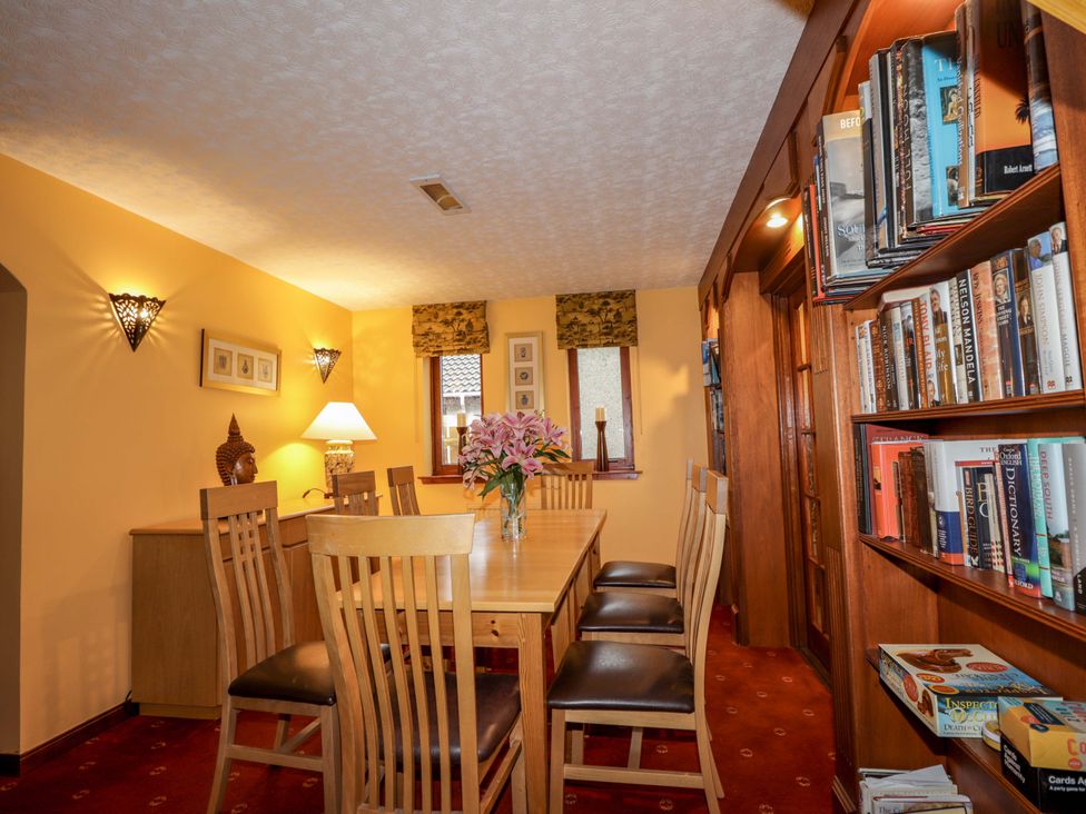 A dining room with a table and bookshelves at Dunhallin House in Inverness