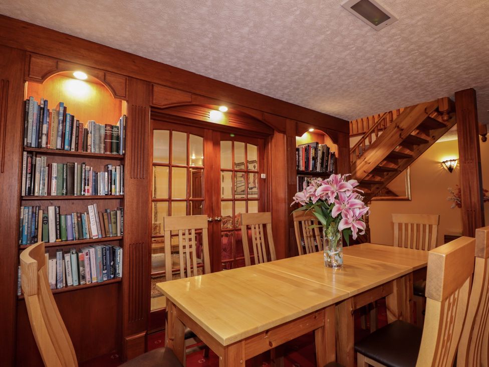 A dining room with a table, chairs, and a bookshelf at Dunhallin House in Inverness