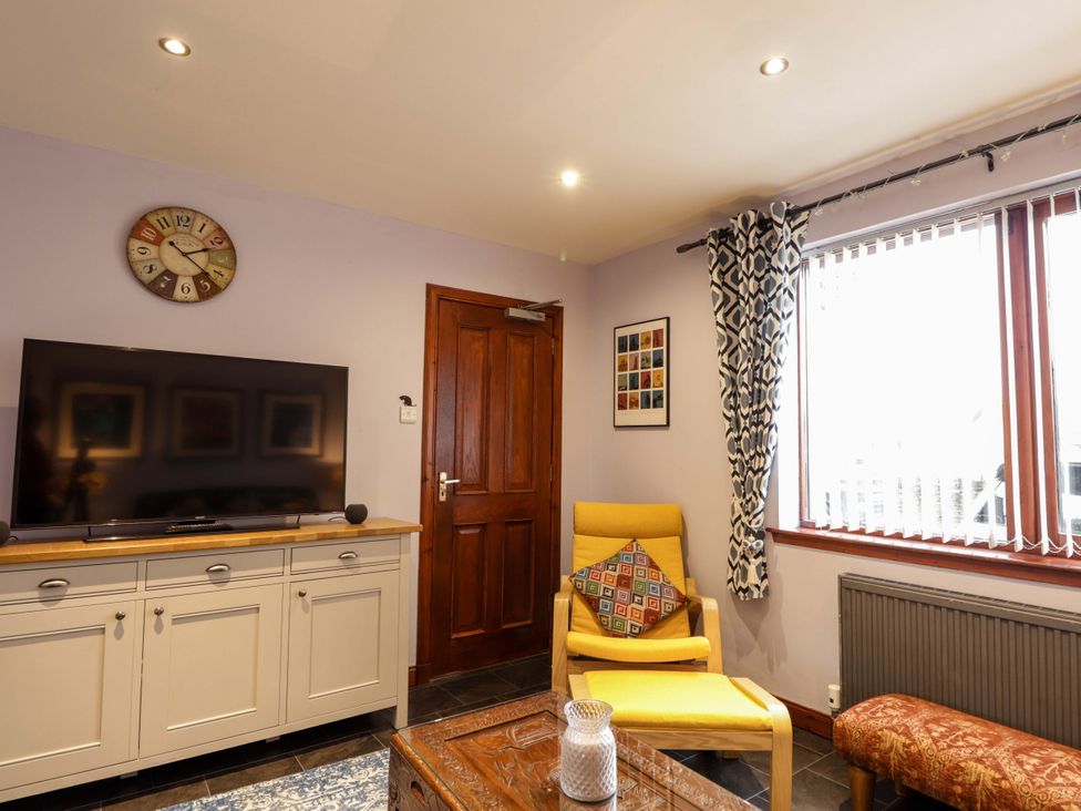 A living room with a television and chair at Dunhallin House in Inverness