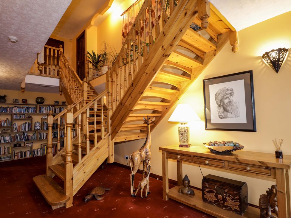 A hallway with a staircase and a bookshelf at Dunhallin House in Inverness