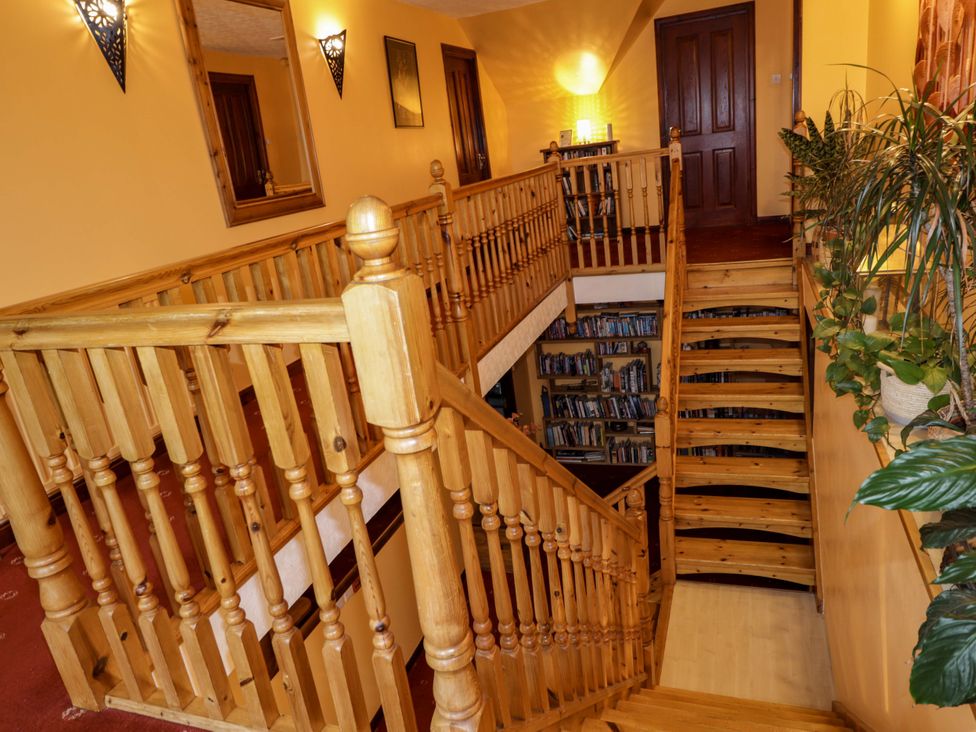 A hallway with a staircase and bookshelf at Dunhallin House in Inverness