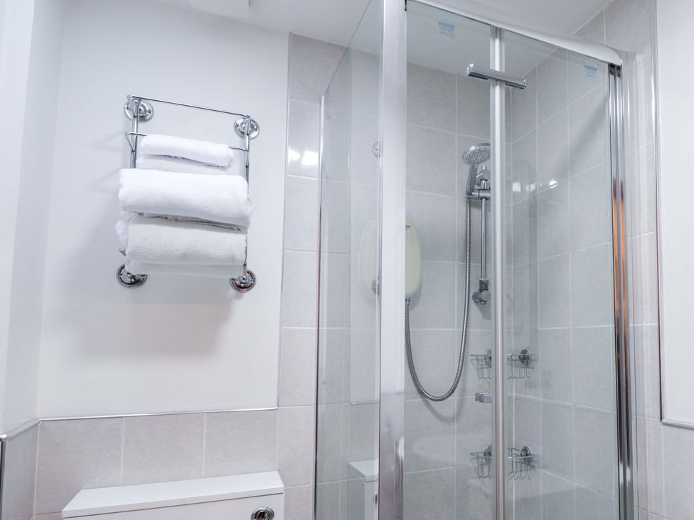 A bathroom with a shower and towels at Dunhallin House in Inverness