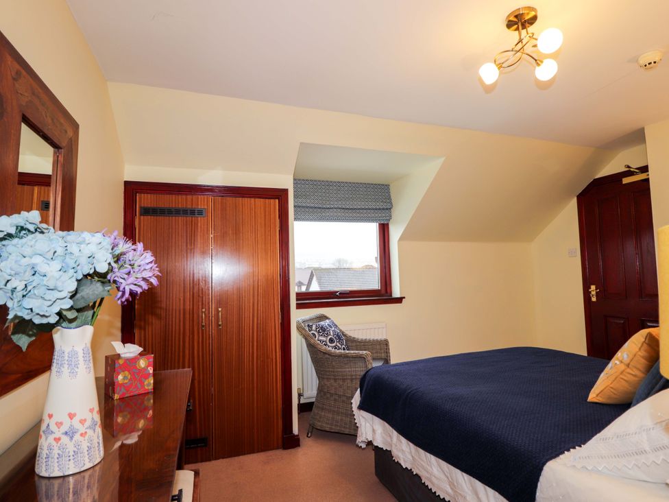 A bedroom with a bed and a mirror at Dunhallin House in Inverness