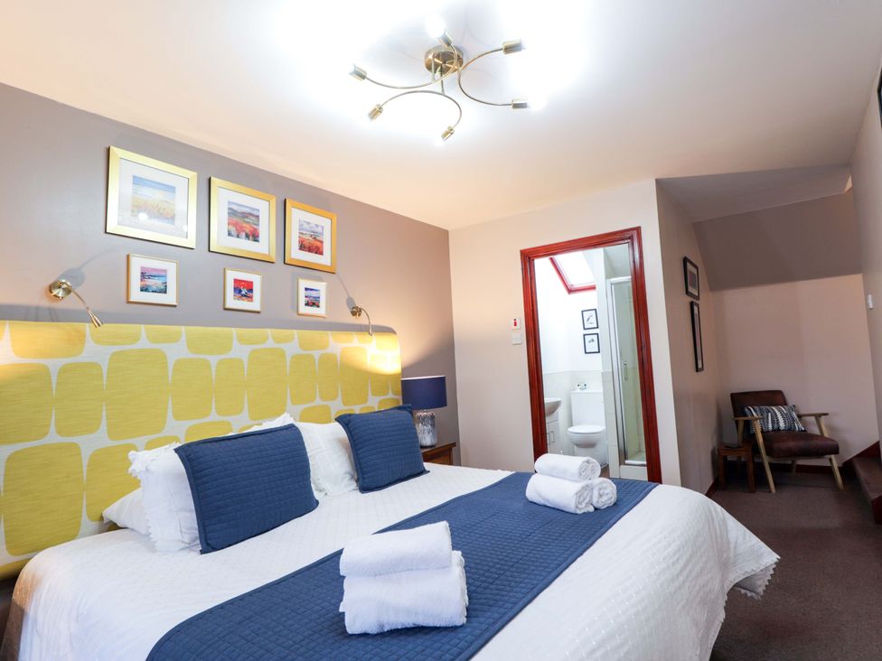 A bedroom with a bed and bathroom entrance at Dunhallin House in Inverness