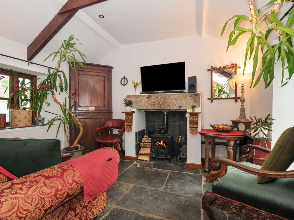 A living room with a fireplace and a television at Coach House in Camelford