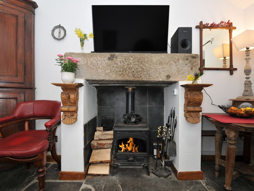 A living room with a fireplace and television at Coach House in Camelford