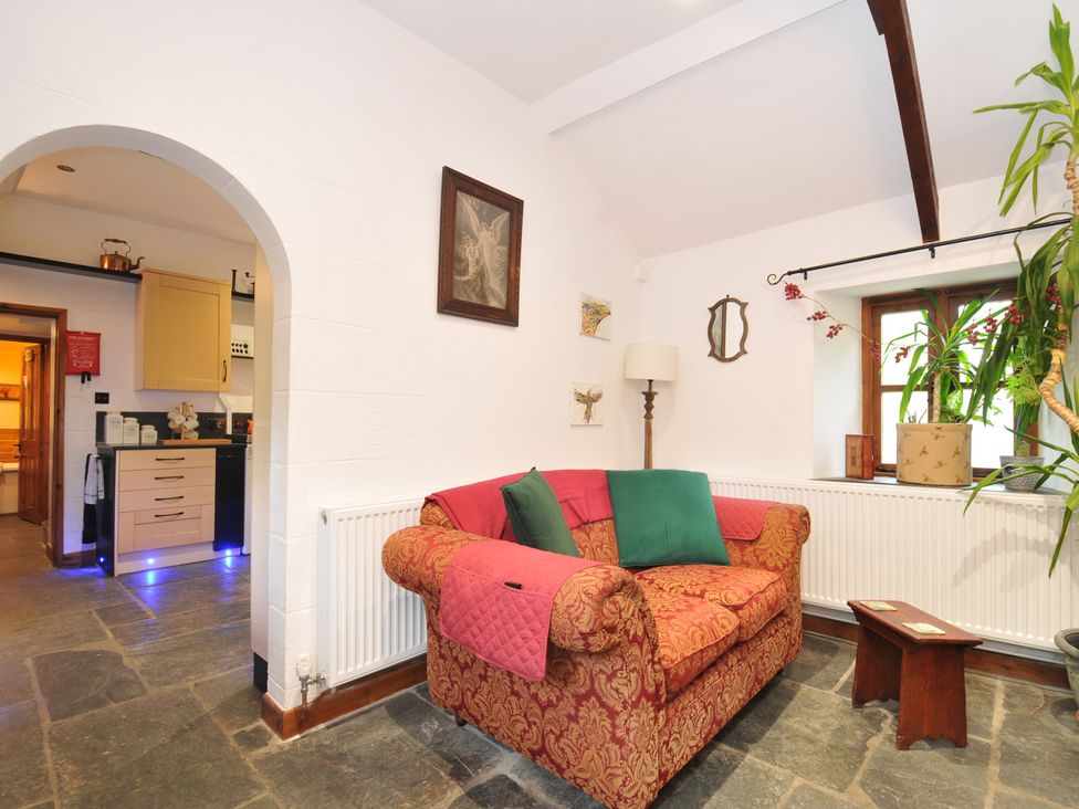 A living room with a sofa and lamp at Coach House, Camelford