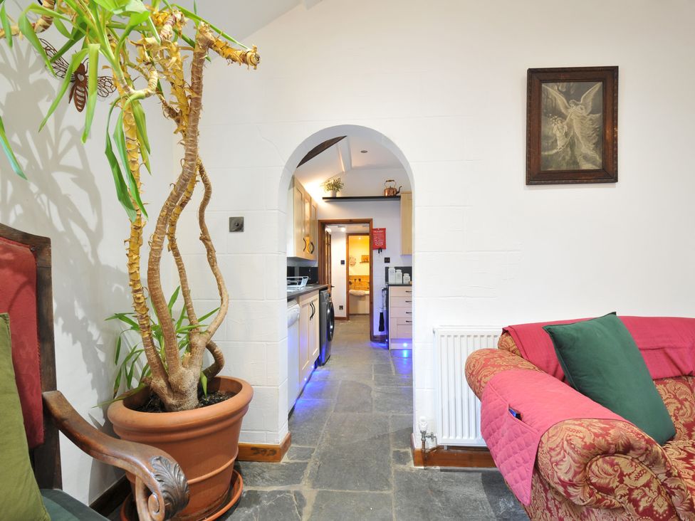 A living room with an archway leading to a kitchen at Coach House in Camelford