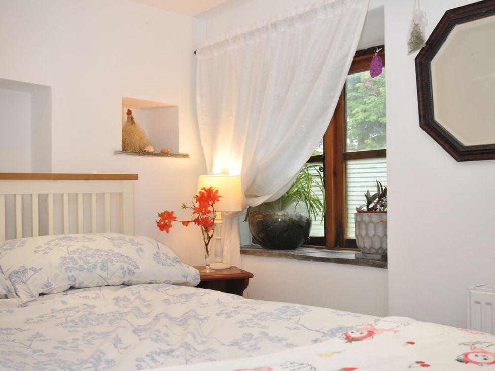 A bedroom with a bed and window at Coach House in Camelford