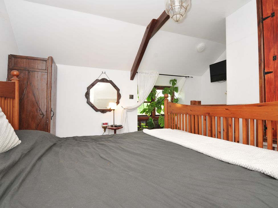 A bedroom with a bed and wardrobe at Coach House in Camelford