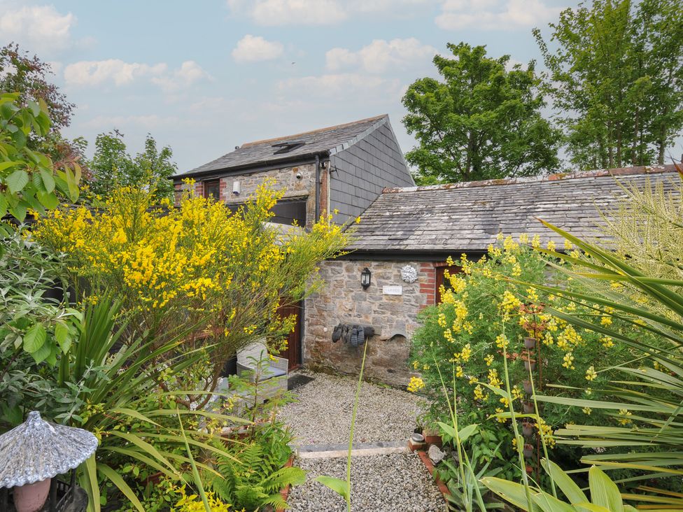 A garden with plants and a building at Coach House Camelford