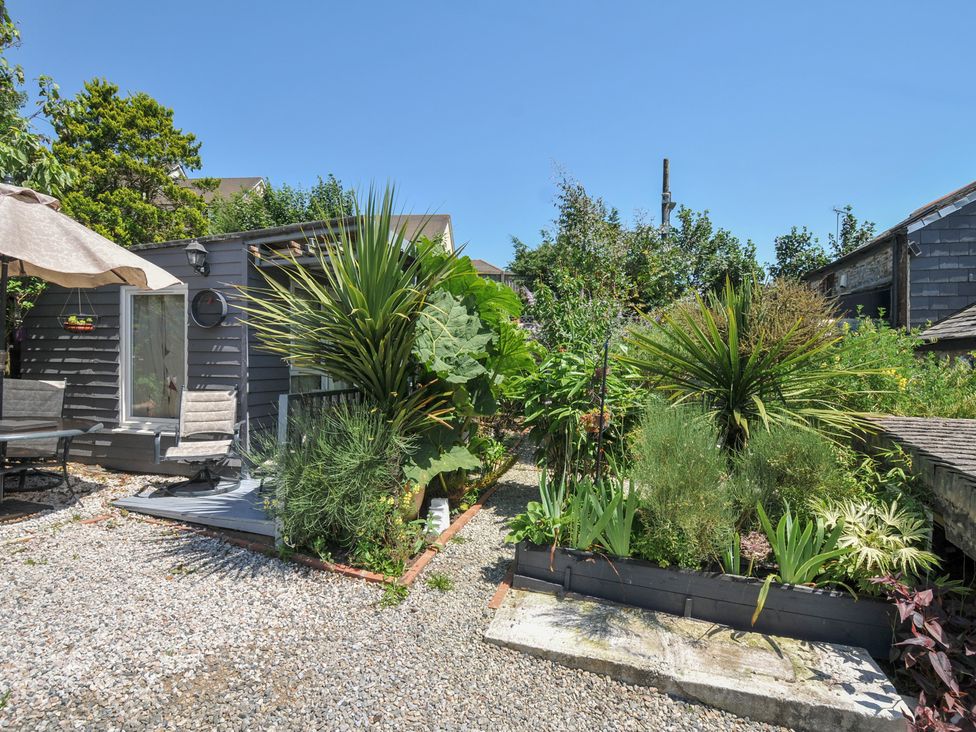 A garden with plant beds and outdoor seating at Coach House in Camelford