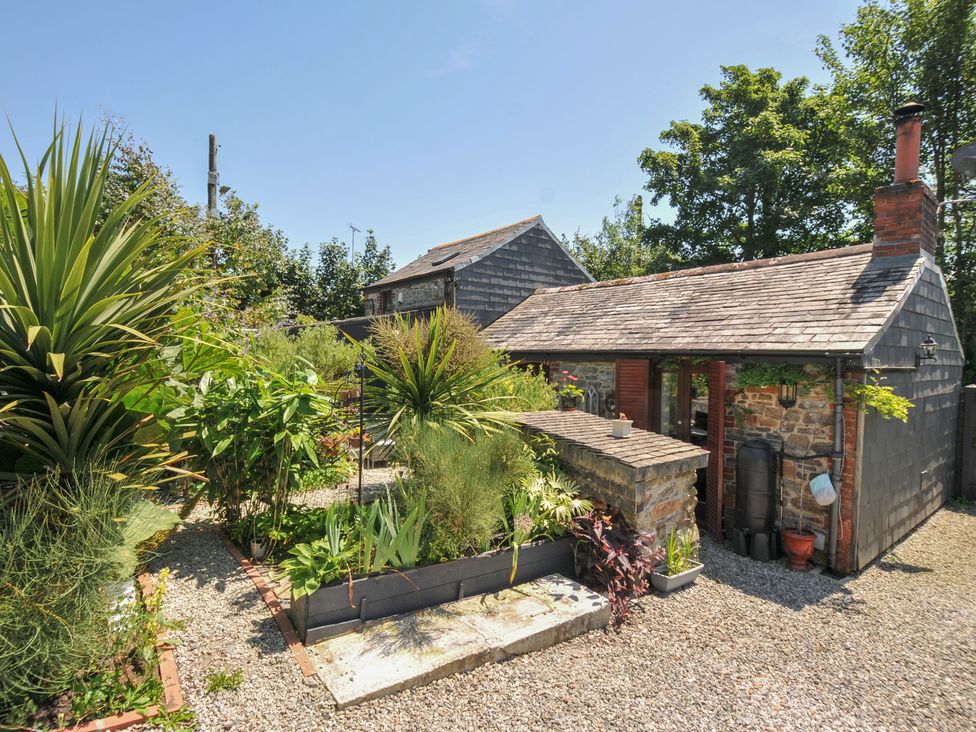 A garden with various plants and a stone structure at Coach House in Camelford