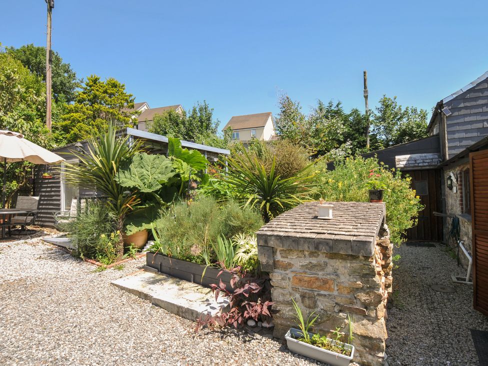 A garden with plants and a table at Coach House in Camelford