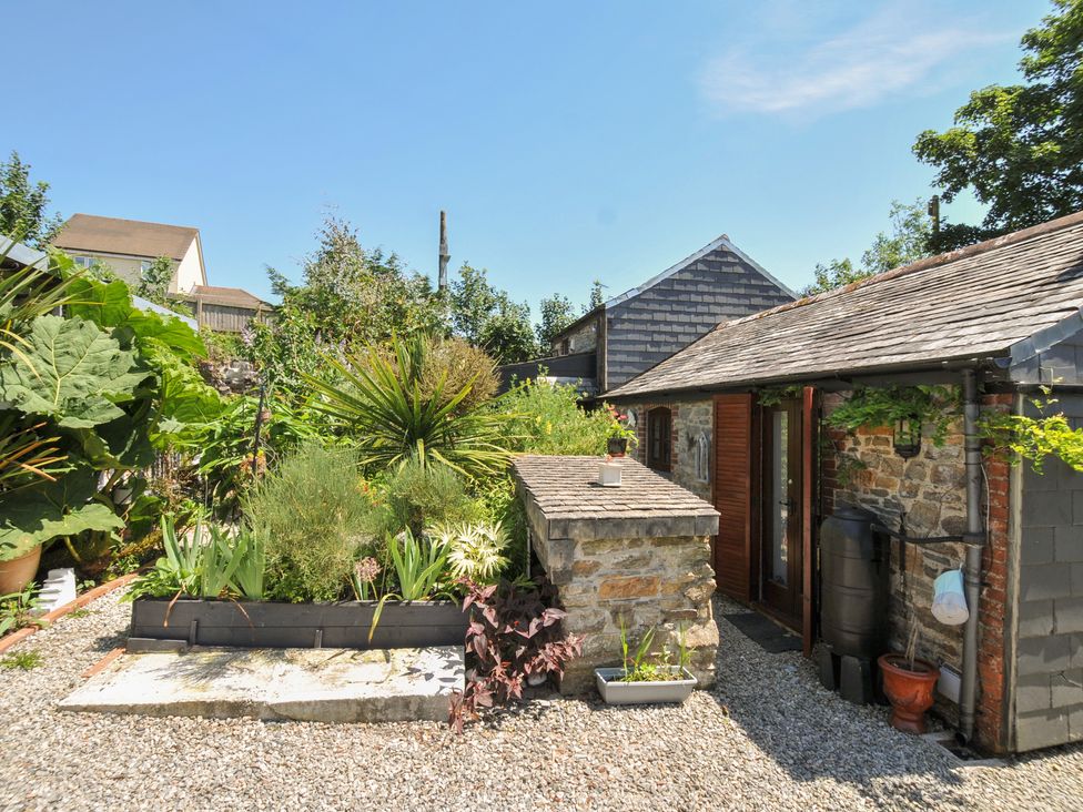 A garden with various plants and a building at Coach House in Camelford