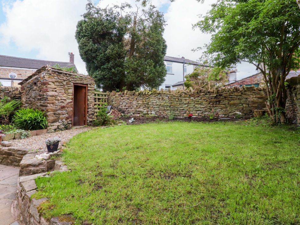 A garden with a stone wall and a shed at 6 Hazel Moor Blackburn