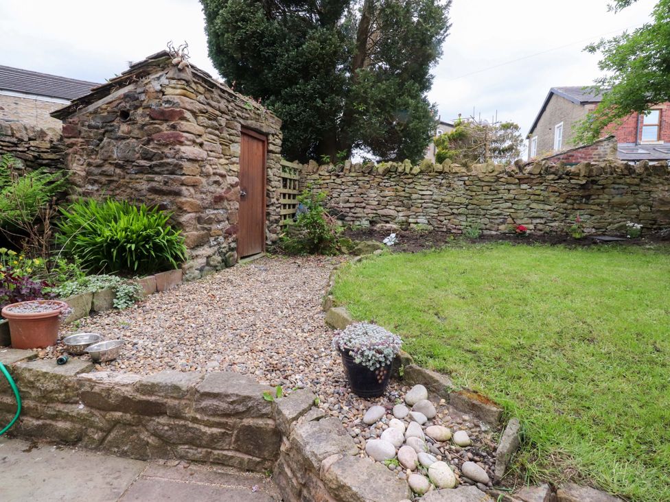 A garden with a stone shed and a gravel pathway at 6 Hazel Moor Blackburn