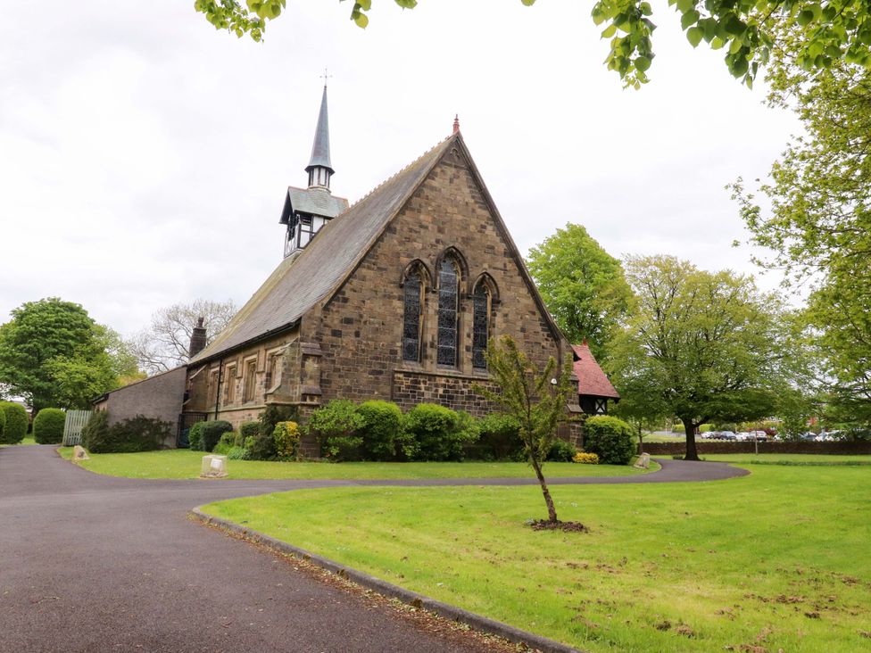 A church building with a steeple and trees at 6 Hazel Moor in Blackburn