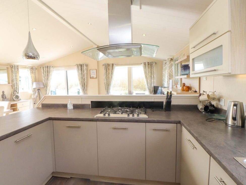 A kitchen with a gas stove and large window at 56 The Stables 