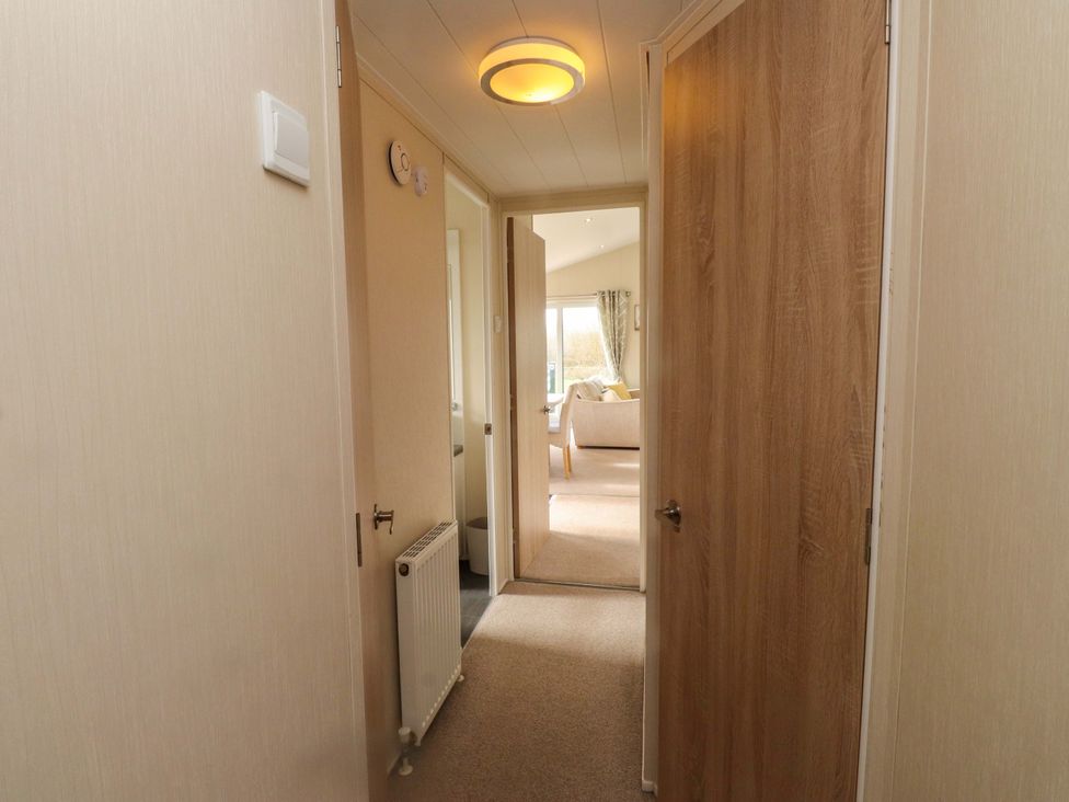 A hallway with doors and a radiator at 56 The Stables in 