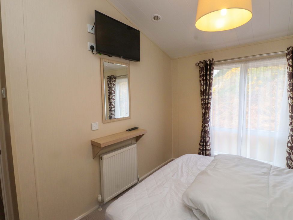 A bedroom with a television and a mirror at 56 The Stables