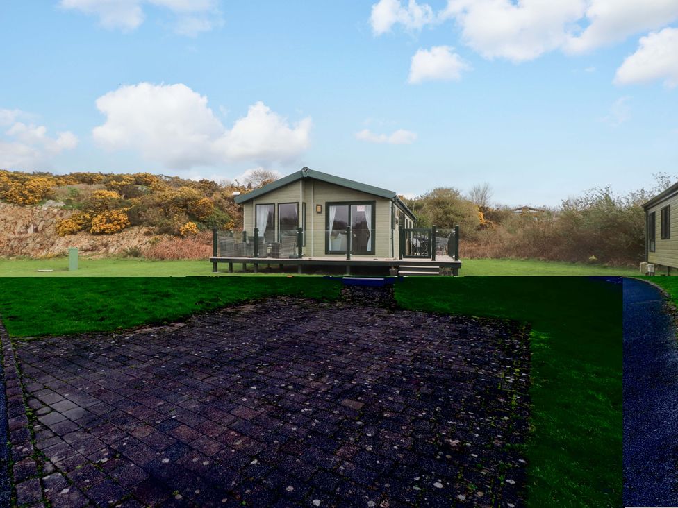 A cabin with a deck surrounded by grass at 56 The Stables