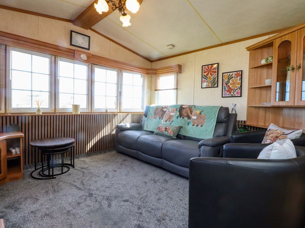 A living room with a sofa and large windows at Caravan at Argraig Llanrhyddlad near Cemaes Bay