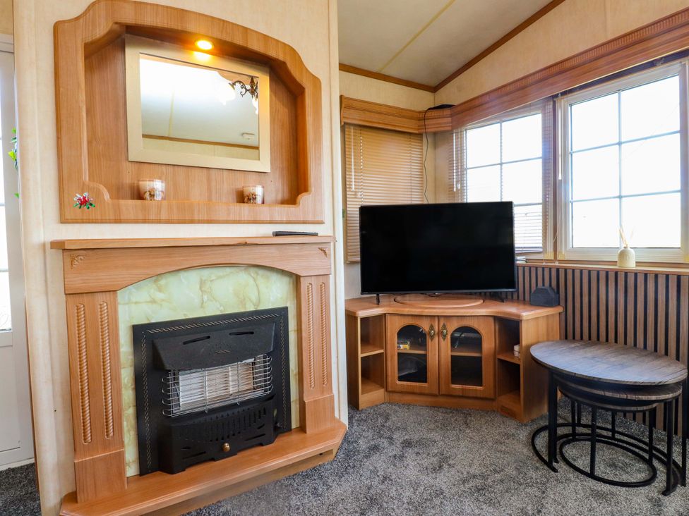 A living room with a fireplace and television at Caravan at Argraig in Llanrhyddlad near Cemaes Bay