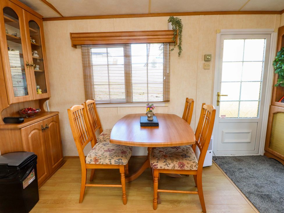 A dining room with a table and chairs at Caravan at Argraig Llanrhyddlad near Cemaes Bay