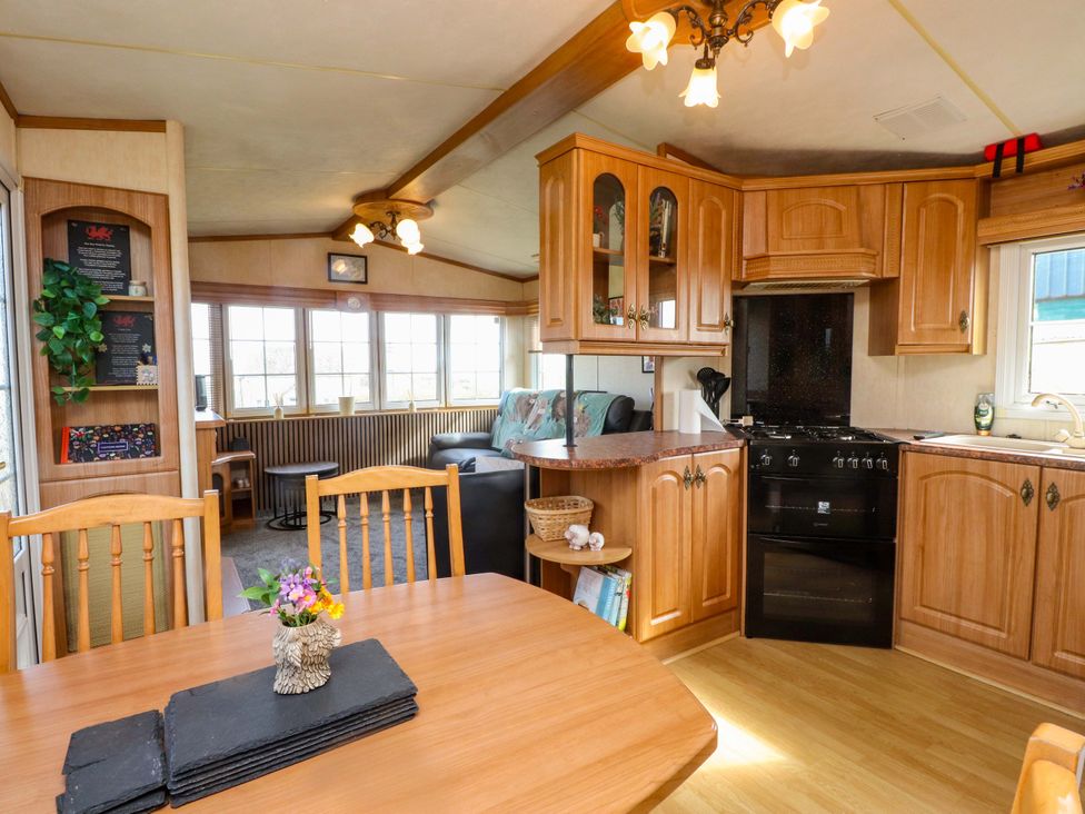A kitchen with wooden cabinets and a table at Caravan at Argraig Llanrhyddlad near Cemaes Bay