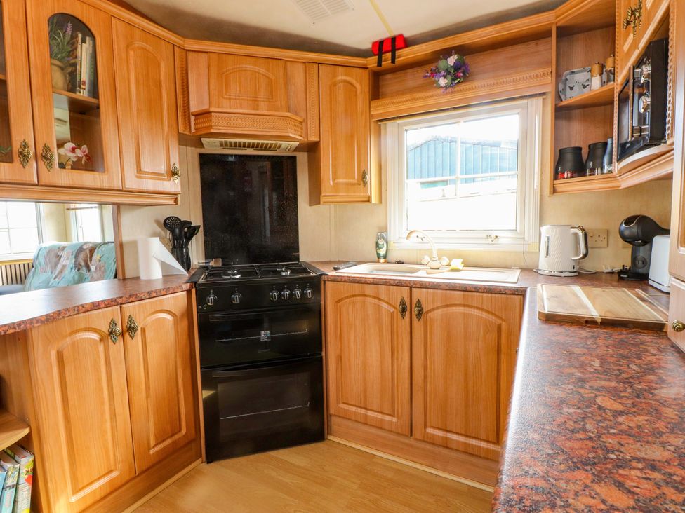 A kitchen with wooden cabinets and stove at Caravan at Argraig Llanrhyddlad near Cemaes Bay